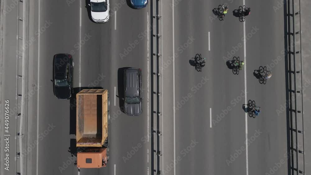 Aerial view from a drone to a group of cyclists on bicycles ride on the road with traffic Aerial view from a drone to a group of cyclists on bicycles ride on the road with traffic
