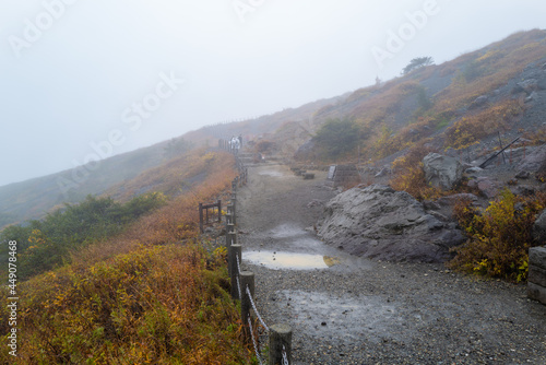 栃木県那須郡那須町の那須岳に霧の中で紅葉を見るために登山している風景 A view of climbing Mt. Nasu in Nasu-machi, Nasu-gun, Tochigi Prefecture, to see the autumn leaves in the fog. photo