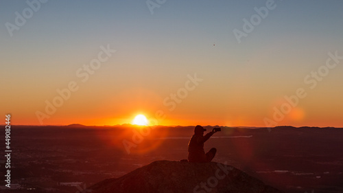 Pessoa curtindo o p  r do Sol no alto de uma montanha.