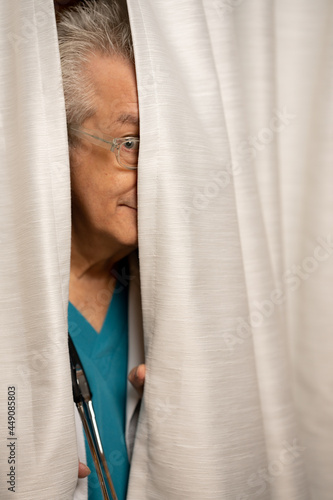 Photo of a doctor hiding in his office behind the curtains photo