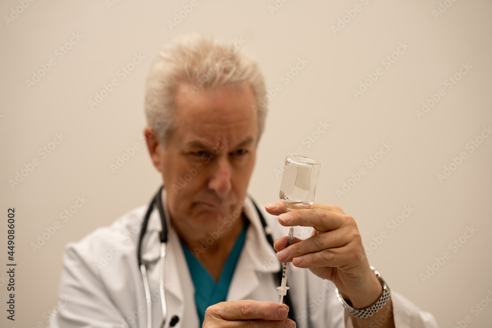 Doctor filling a needle with medicine from a glass vial Doctor filling a needle with medicine from a glass vial