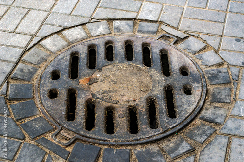 Metal covers of sewer manholes on city roads close-up.