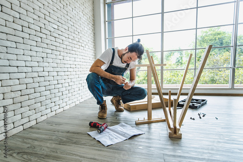 Hipster young man working as handyman looking to manual during assembling wood table with equipments, concept for home diy and self service.in the office © Bangkok Click Studio