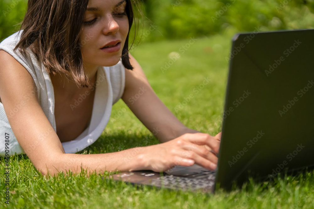 A young girl in a white dress is working on a laptop. A young girl in a white dress is working on a laptop.