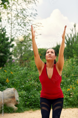 Middle-aged Asian woman doing yoga in the park on the sand among the trees, the concept of yoga, meditation, relaxation.