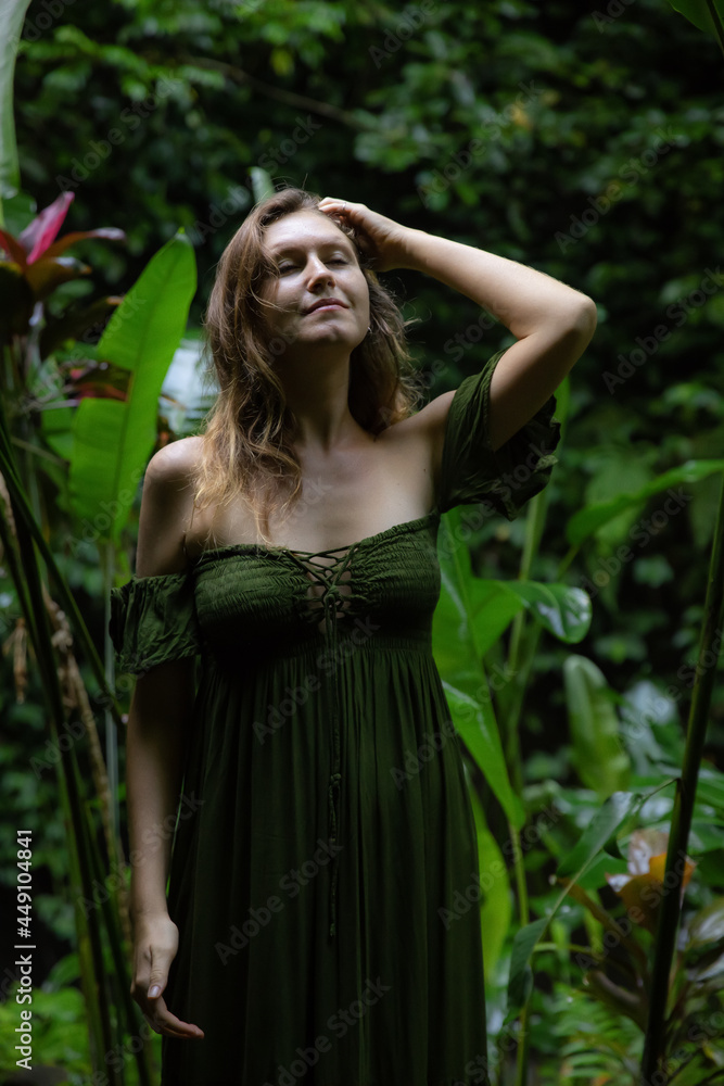 Beautiful woman walking in tropical rain forest, wearing green dress. Woman in jungle. Closed eyes. Nature and environment concept. Travel to Asia. Bali, Indonesia Beautiful woman walking in tropical rain forest, wearing green dress. Woman in jungle. Closed eyes. Nature and environment concept. Travel to Asia. Bali, Indonesia