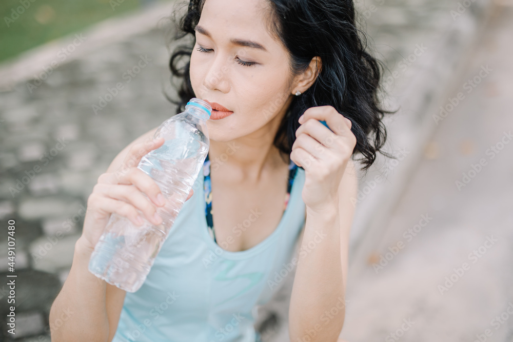 A pretty woman holding a water bottle with a smile. concept of health care and drinking clean water A pretty woman holding a water bottle with a smile. concept of health care and drinking clean water