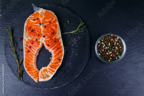 Raw salmon steak with spices on black slate. Top view
