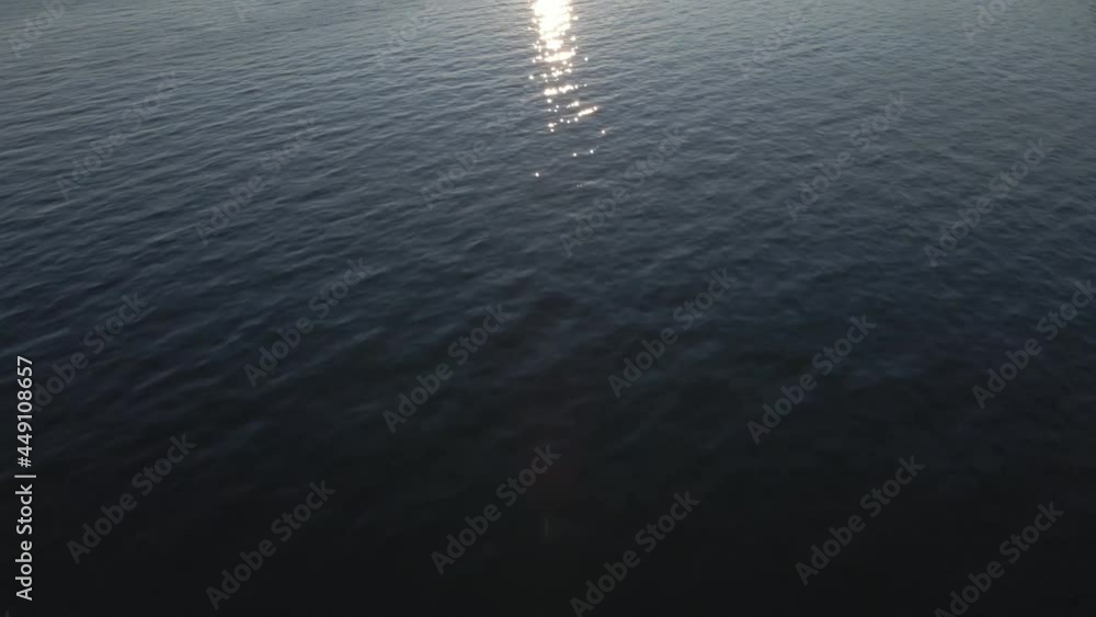 A slow panning up shot over a lake revealing in a warm and calming sunrise of light over a bay of trees and buildings A slow panning up shot over a lake revealing in a warm and calming sunrise of light over a bay of trees and buildings