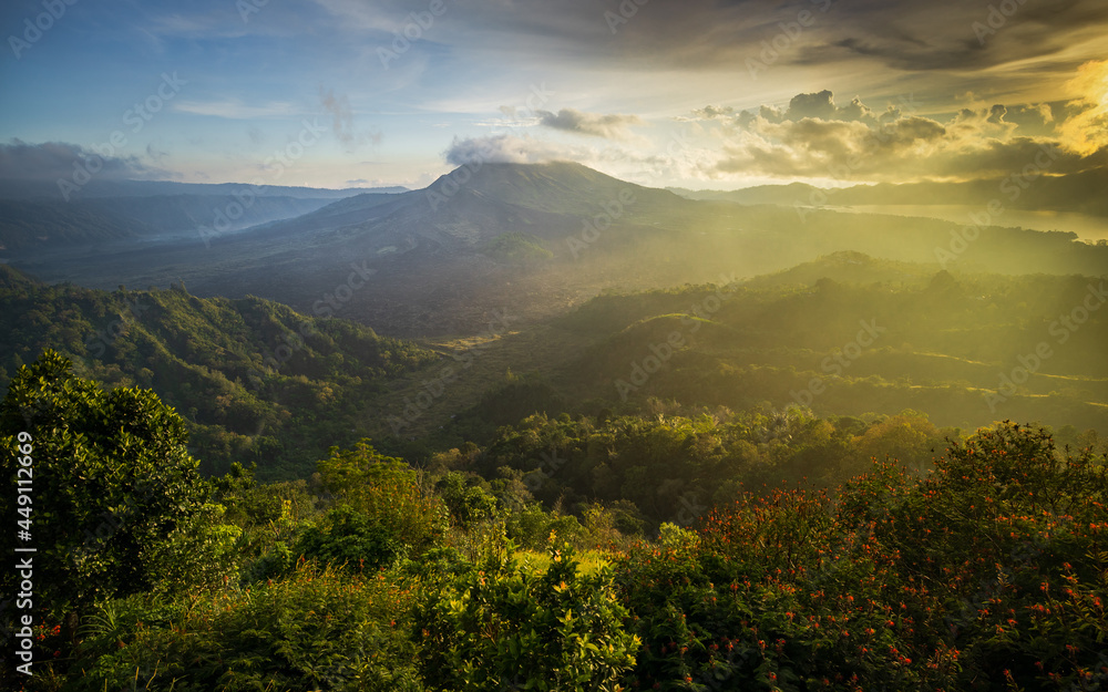 Fototapeta premium Beautiful mountain landscape during sunrise. Hills, Batur volcano and lake. Scenic panoramic view. Colorful sky with clouds. Foggy morning. Kintamani, Bali