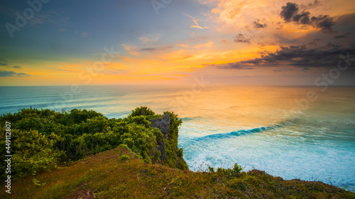 Seascape. Spectacular view from Uluwatu cliff in Bali. Sunset time. Blue hour. Ocean with motion foam waves. Cloudy sky. Nature concept. Soft focus. Slow shutter speed.