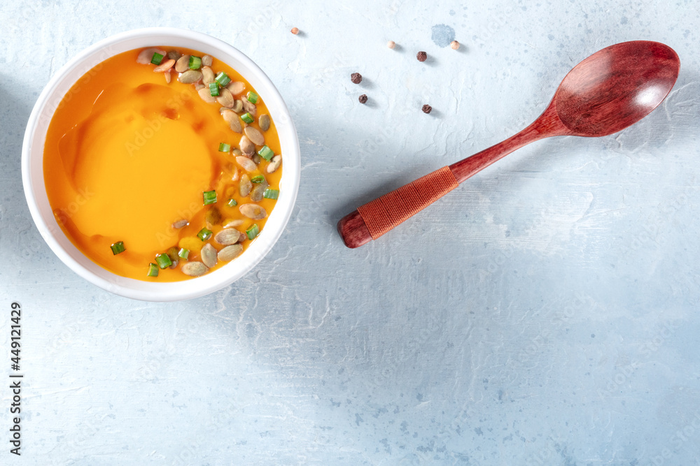 Pumpking soup with black pepper and a wooden spoon, top shot with copy space. Healthy vegan dinner