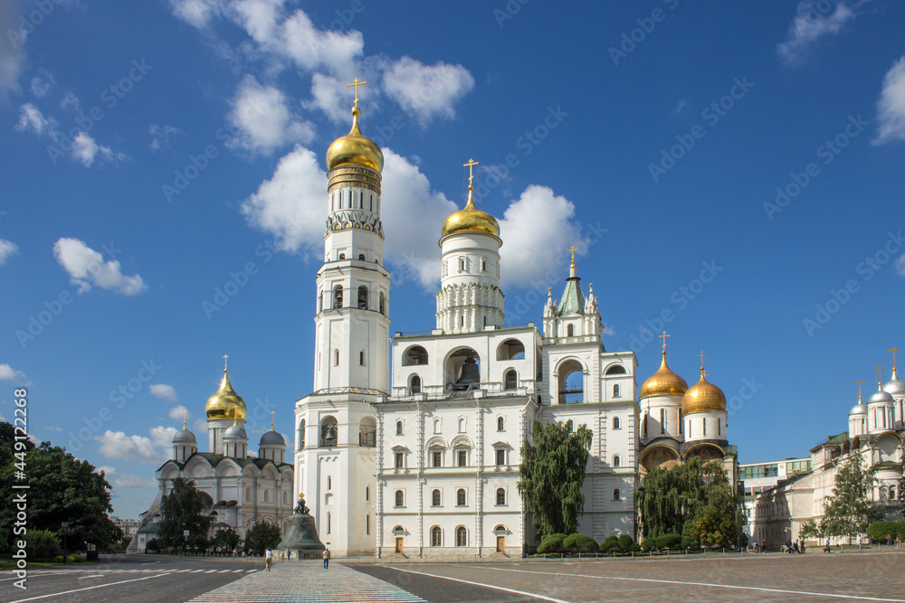 MOSCOW, RUSSIA-AUGUST, 4, 2021: the white-stone high bell tower of Ivan the Great with golden domes on Cathedral Square on a bright sunny summer day