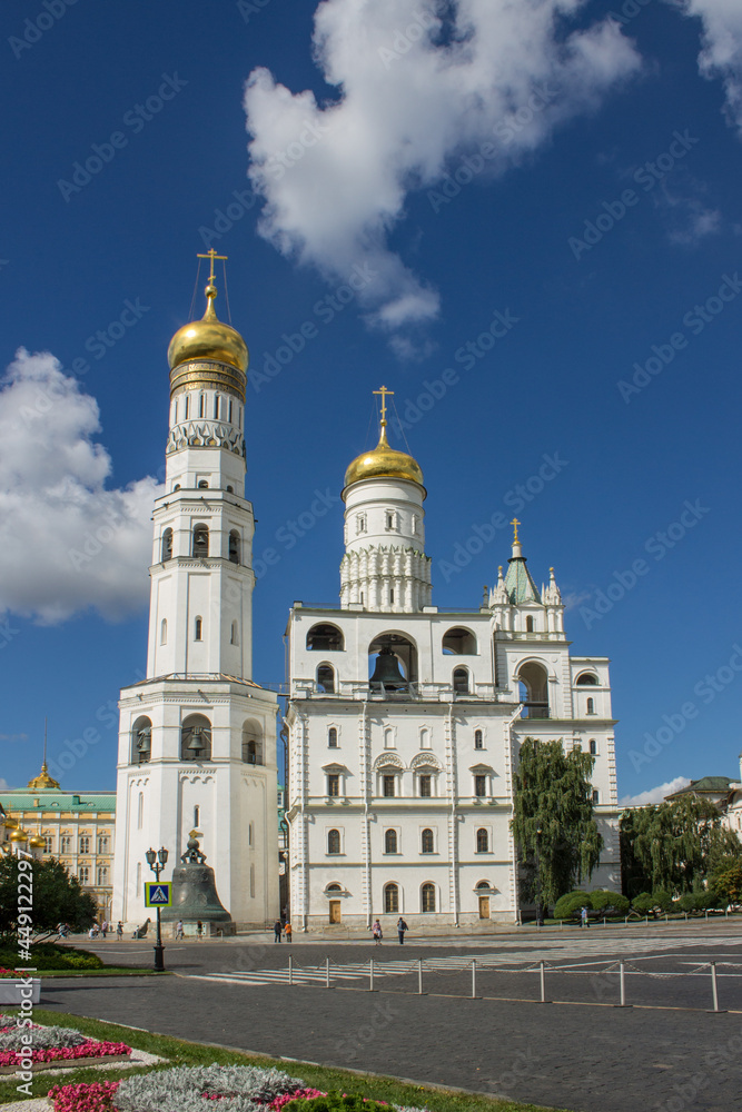 view of the white-stone bell tower of Ivan the Great with golden domes in the Kremlin on Sobornaya Square on a bright sunny summer day in Moscow Russia