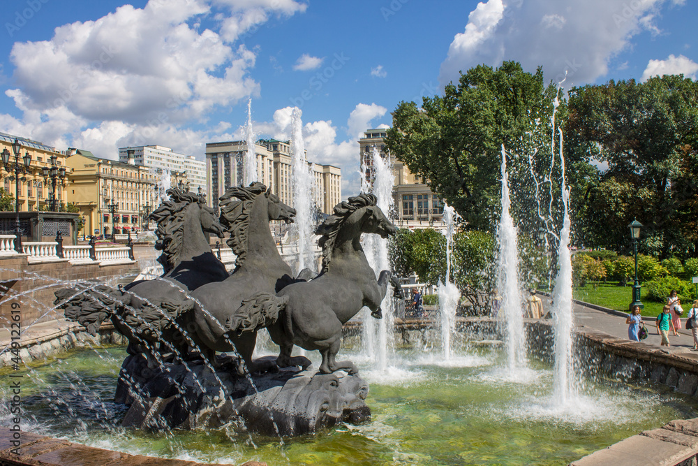MOSCOW, RUSSIA-AUGUST, 4, 2021: the famous fountain on Manezhnaya Square - three horses and splashing water jets on a sunny summer day
