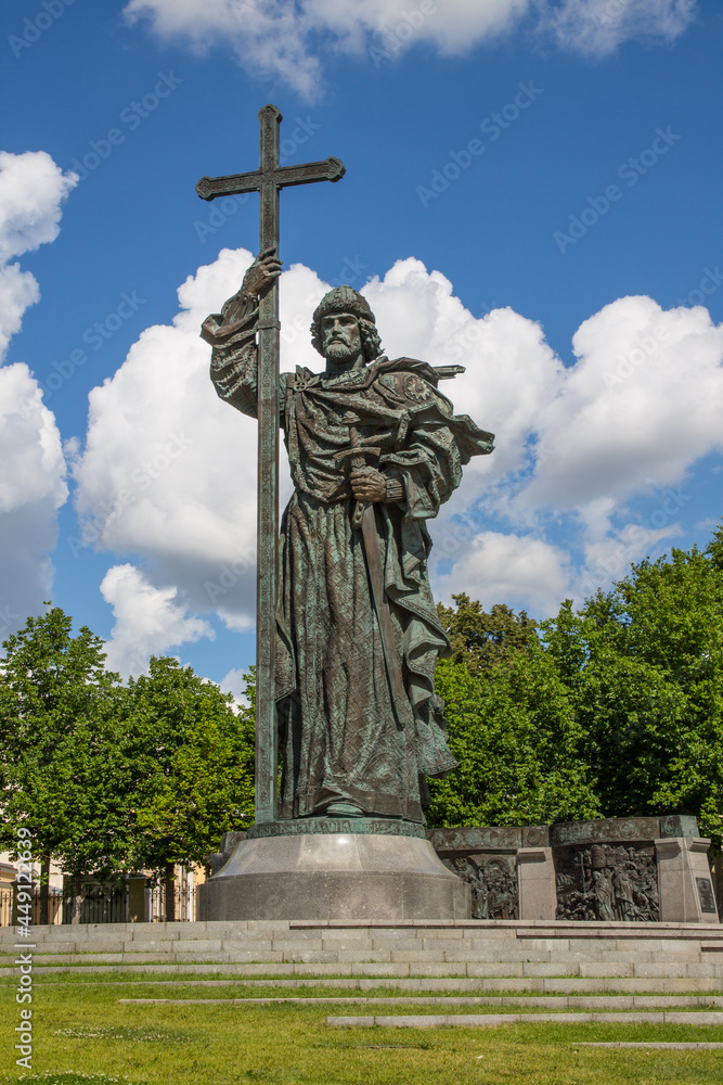 bronze monument to Prince Vladimir with a Christian cross in the historical center of the capital against the background of a bright blue cloudy sky on a sunny summer in Moscow Russia