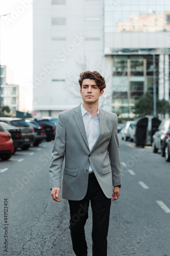 young man in casual suit walking down a street