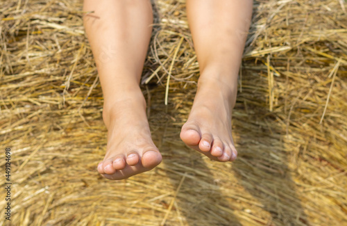 bare feet of girl's on a haystack in sunset