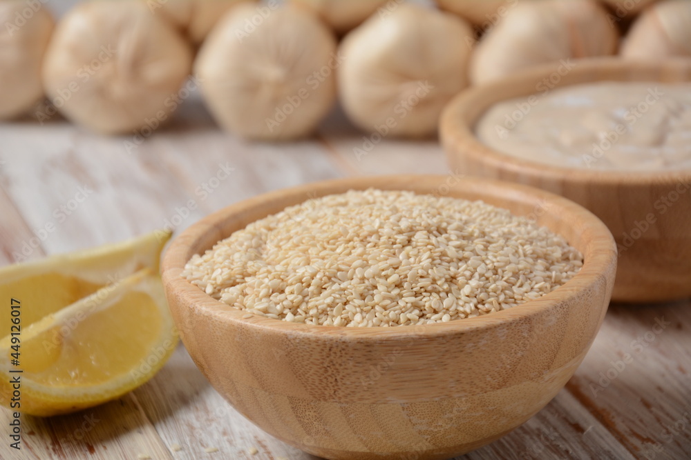 Wooden bowl and spoon with white sesame seeds on vintage wooden background Wooden bowl and spoon with white sesame seeds on vintage wooden background