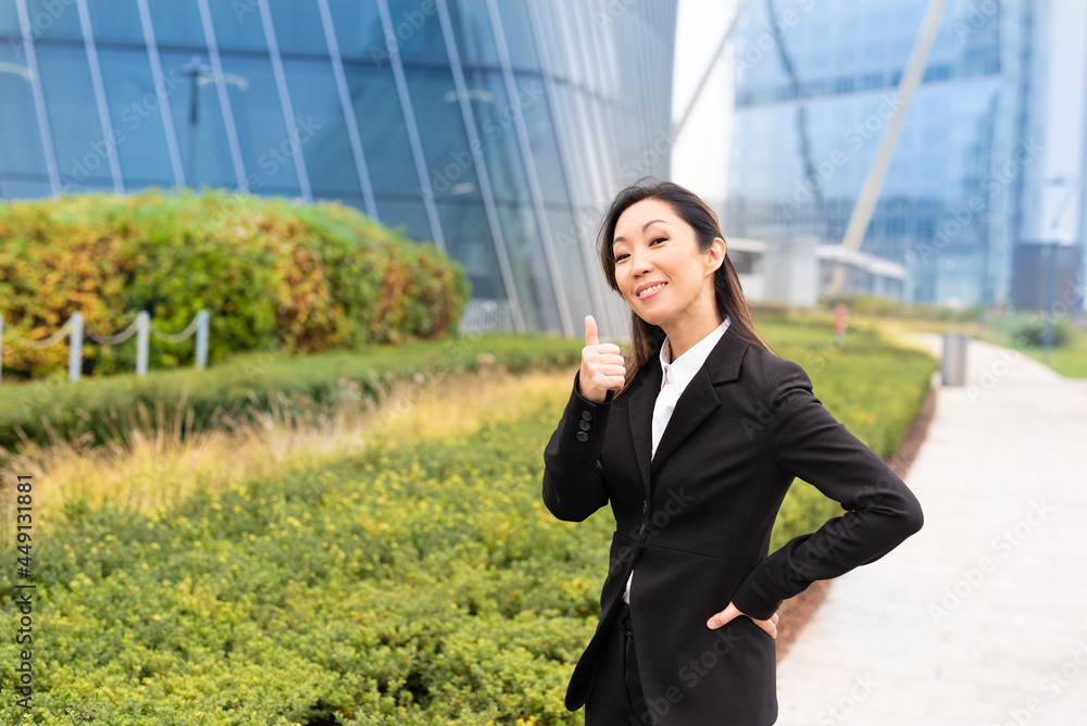 smiling Asian business woman showing her thumbs up, financial success concept, green economy, equal rights of women smiling Asian business woman showing her thumbs up, financial success concept, green economy, equal rights of women