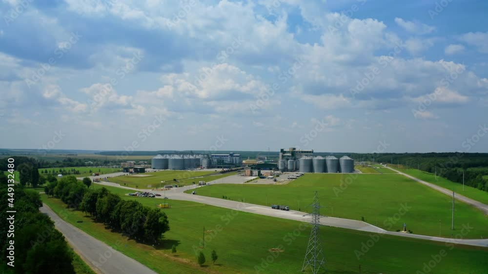 Modern factory among fields. Grain elevators for keeping agricultural products. Grain storage tank in the countryside. Aerial view Modern factory among fields. Grain elevators for keeping agricultural products. Grain storage tank in the countryside. Aerial view