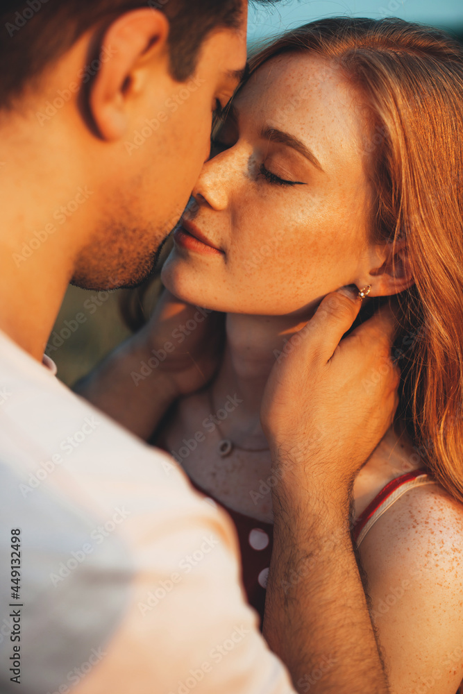 Naklejka premium Close up photo of a caucasian ginger woman with freckles kissing and embracing in the sunshine