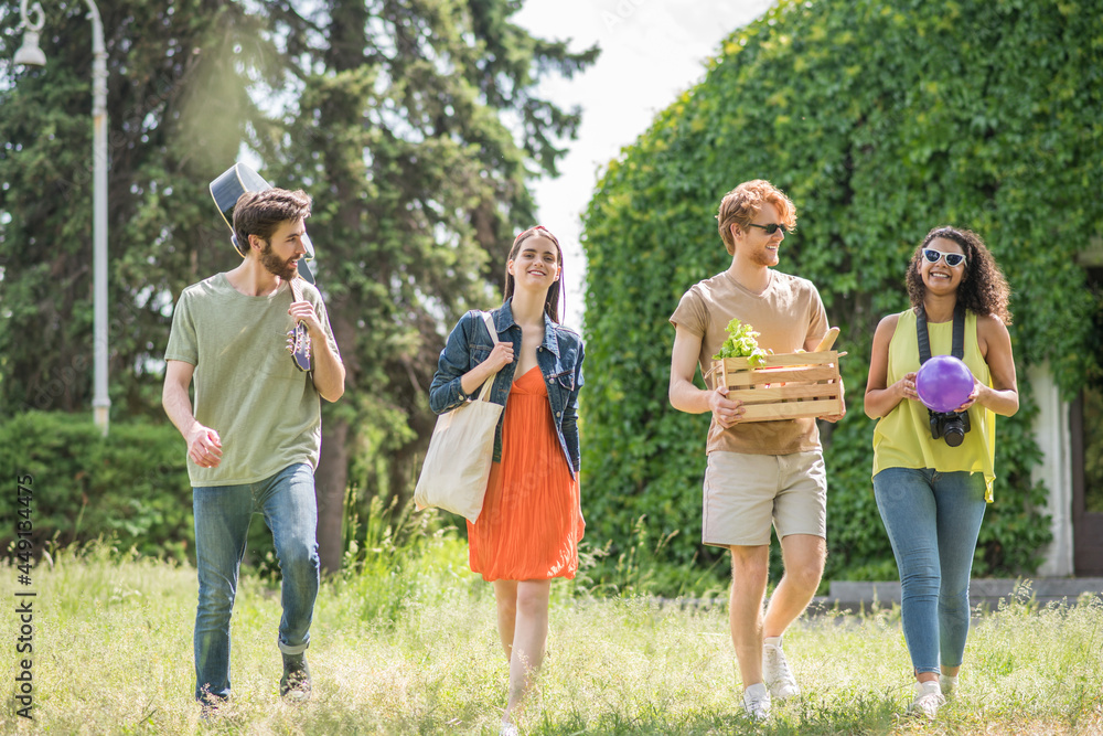Fototapeta premium Young people walking on summer picnic in park