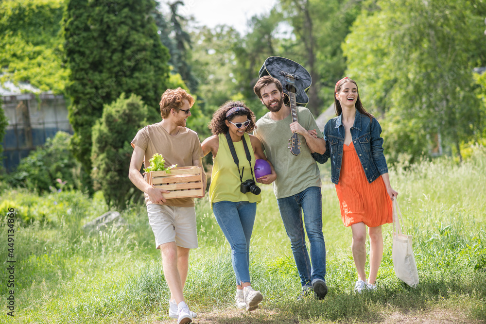 Four friends walking in park for picnic Four friends walking in park for picnic