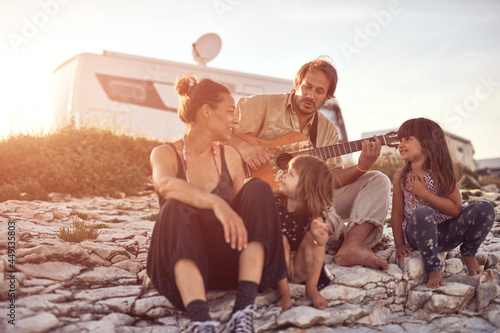 Family on a vacation, singing, playing music on a guitar and enjoying summertime vibes. © astrosystem