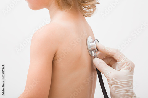 Tablou pe pânză Doctor hand in protective glove holding stethoscope and listening child lungs noise from back