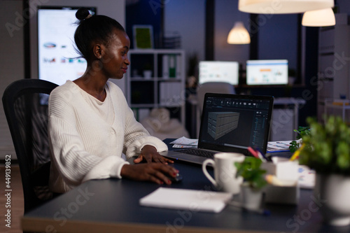 Technician engineer analyzing cad software 3D concept of container working in start-up company late at night. African american woman developing industrial prototype using construction technology