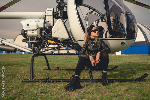 Blonde preteen girl sitting on footboard of helicopter at airfield photo