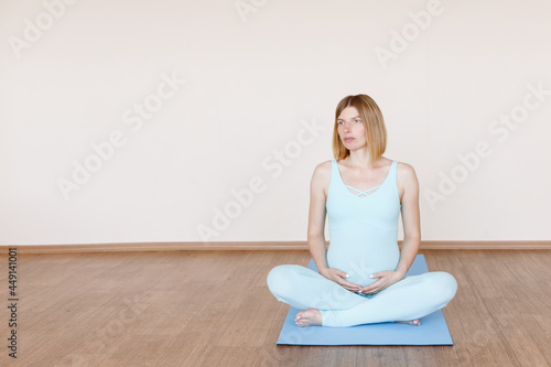 pregnant woman in lotus position on a mat in a bright studio