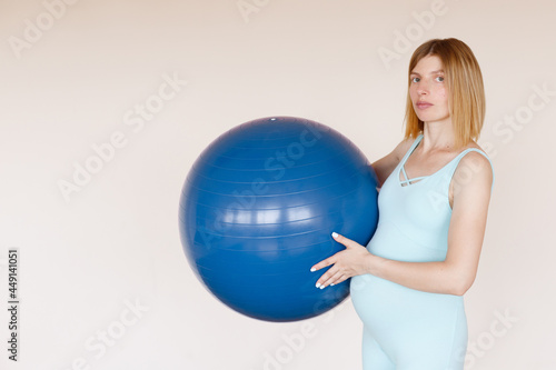 pregnant woman in blue jumpsuit with fitness ball in training