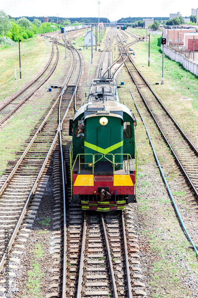 Naklejka premium A shunting locomotive moves along the railroad from the station to sort the railroad cars. Railway tractor for joining wagons into a train.