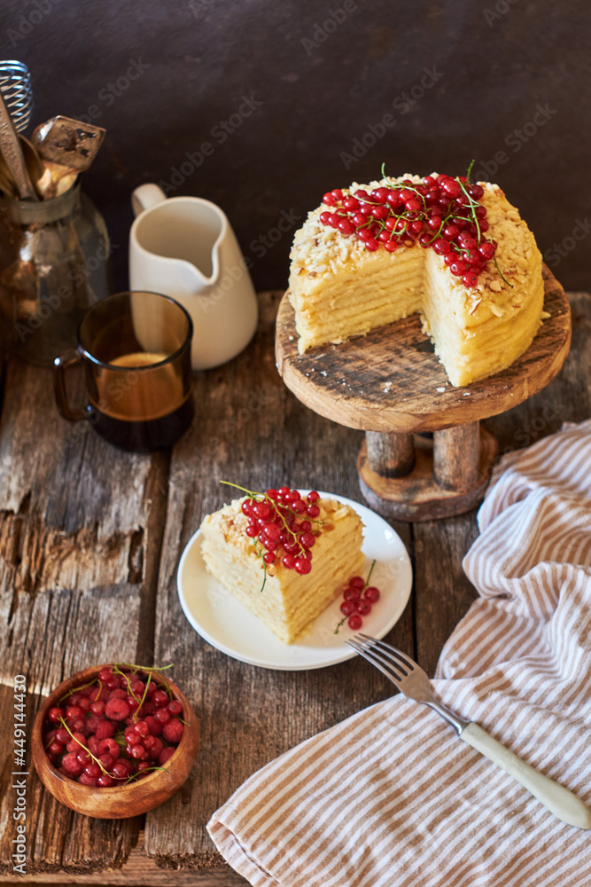 Cake on a wooden cake stand. Shortcrust pastry cake, decorated with red currants. Wooden background, side view.