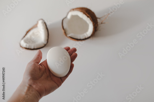 hand with a natural coconut soap or shampoo bar on white background