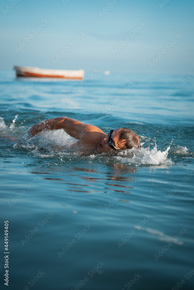 A sports man is engaged in swimming on the sea. Swims crawl across the ocean at dawn