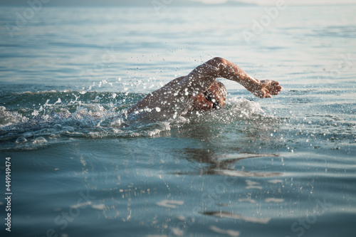 A sports man is engaged in swimming on the sea. Swims crawl across the ocean at dawn
