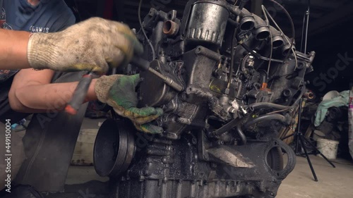 An auto mechanic checks the internal combustion engine. The engine is covered in oil and dirty. Its complete replacement also failed. Auto disassembly or car service .