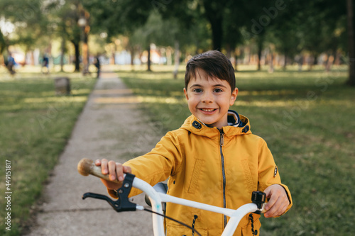 portrait of little boy with his bike, outdoors in public park