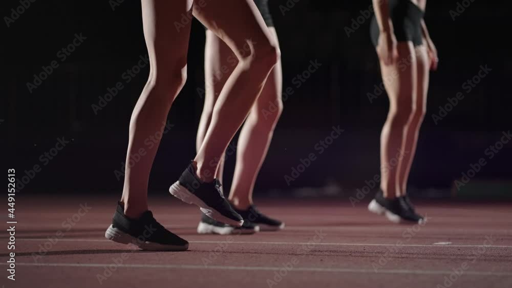 Three women athletes prepare for a track race in a dark stadium with streetlights on. Time-lapse footage of warm-up and concentration of a group of women before the race on the track Three women athletes prepare for a track race in a dark stadium with streetlights on. Time-lapse footage of warm-up and concentration of a group of women before the race on the track