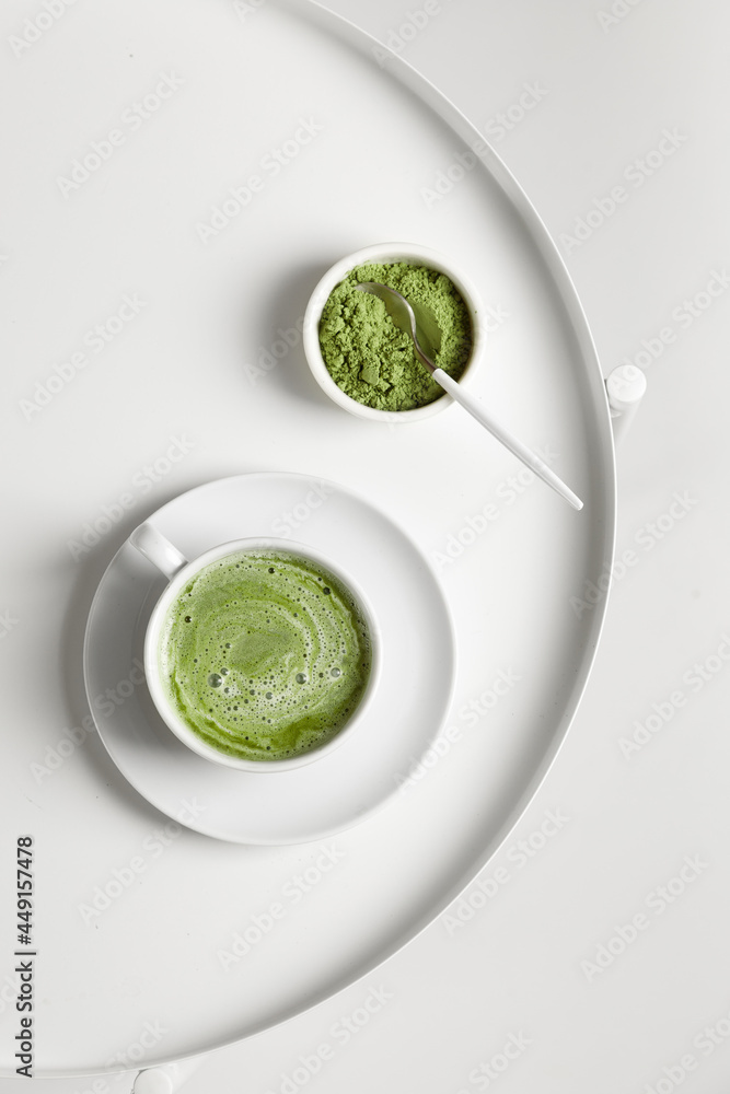 Green matcha tea with milk on cup with spoon on white table Green matcha tea with milk on cup with spoon on white table