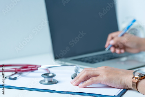 the doctor is analyzing the illness A stethoscope and computer are placed on a white desk in a white background.