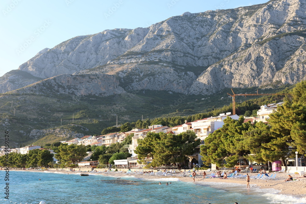 Croatian beach of Tucepi in the evening. Beautiful landscape with shoreline of Makarska Riviera and Adriatic Sea in Croatia on a cloudy day. Seaside view with fresh air from pine trees.