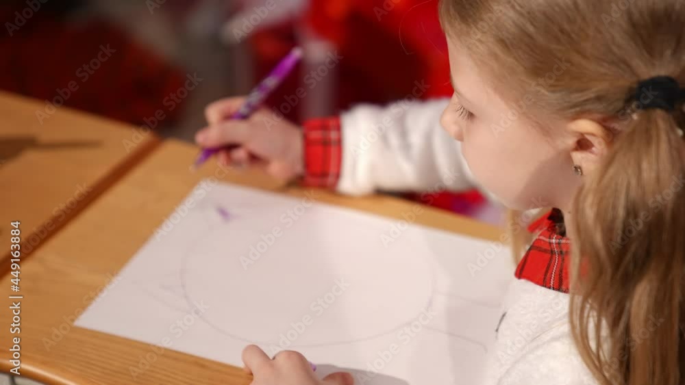 Portrait of a lovely little girl indoors at Christmas. Cute child writing a letter to Santa. Beautiful small girl drawing a picture on xmas background at home Portrait of a lovely little girl indoors at Christmas. Cute child writing a letter to Santa. Beautiful small girl drawing a picture on xmas background at home