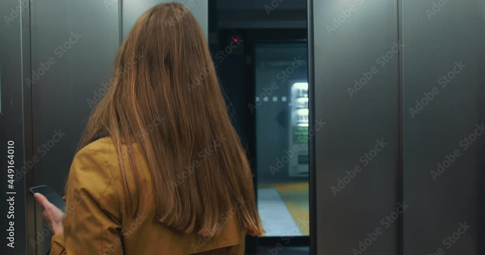 Happy young beautiful business woman in face mask holding smart phone, shopping bags pushes elevator button, leaves. Happy young beautiful business woman in face mask holding smart phone, shopping bags pushes elevator button, leaves.