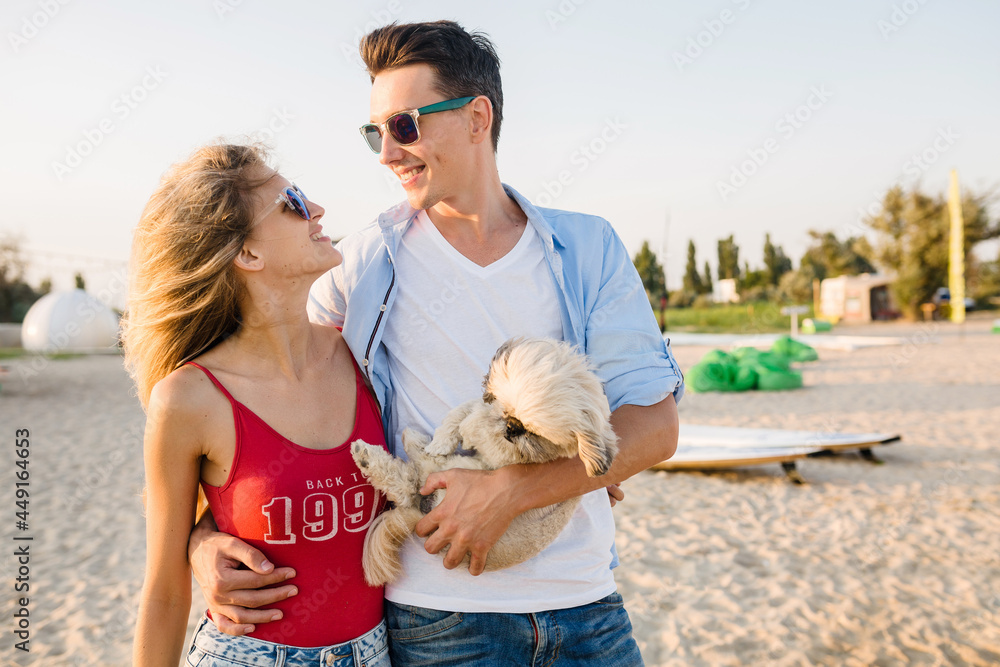 young attractive smiling couple having fun on beach playing with dogs young attractive smiling couple having fun on beach playing with dogs