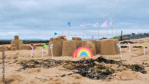 Sand Castle with ramparts and flags and a rainbow door on a beach