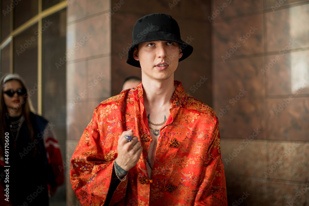 Positive man portrait with dressed in street style clothes red kimono with chains around neck. Youth and lifestyle concept. Luxury rap artist.